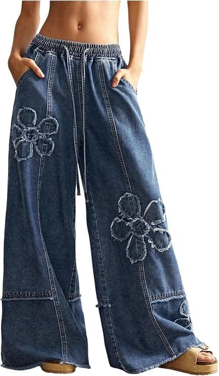 A close-up shot of a model wearing dark wash BEAUDRM Women's Y2K Baggy Jeans Wide Leg Jeans Denim Boho Pants with a drawstring waist and unique floral pattern against a bright backdrop.