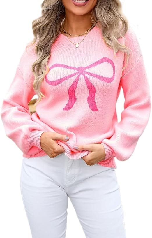A fashion model wearing the pink Sumleno Womens Fall Winter Casual Sweater Cute Bow Crewneck Long Sleeve Baggy Knit Sweatshirt Top Trendy Aesthetic Clothes styled with white jeans, perfect for showcasing a sweet fall casual aesthetics outfit.