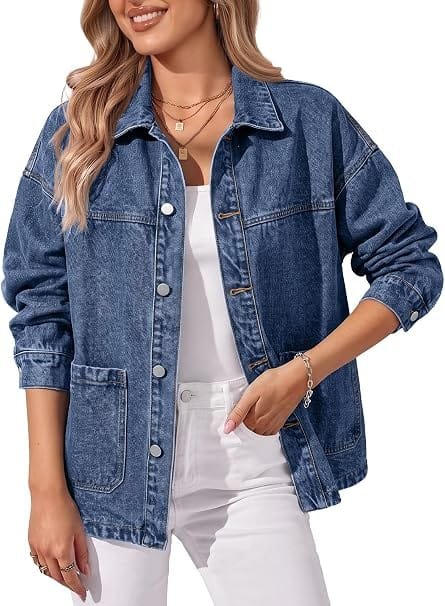 A stylish woman wearing a classic blue Trendy Queen Womens Oversized Jean Jacket over white pants, showcasing a relaxed boyfriend fit against a clean modern background.
