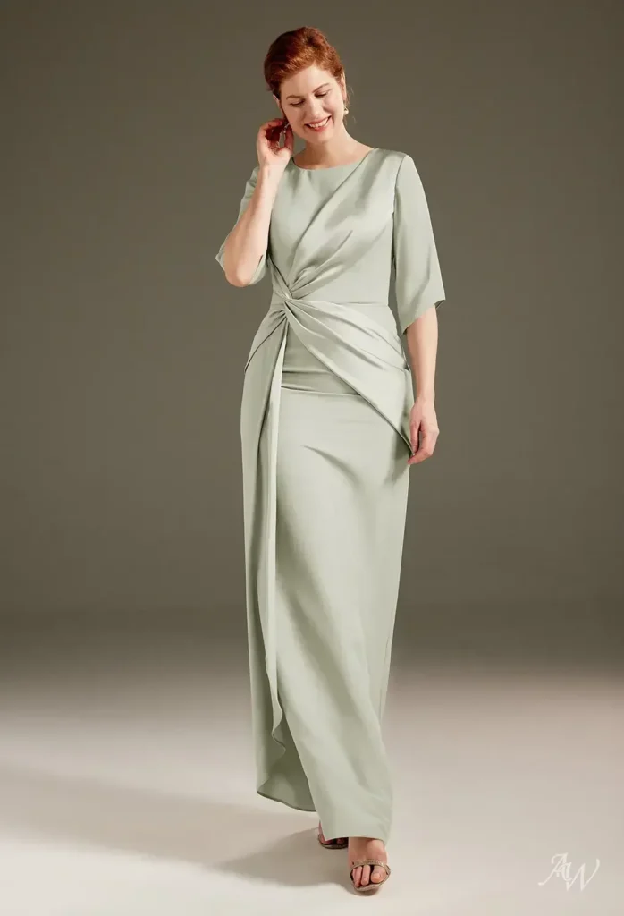 Full-length front view of a model wearing the AW Caesar Dress in sage green satin charmeuse, featuring a refined bateau neckline, 3/4 sleeves, and a stylish twist-draped waist, ideal for formal wedding attire.