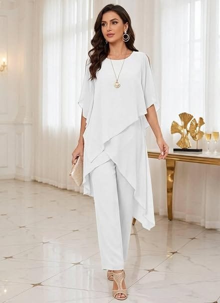 Full-length lifestyle photography of a model wearing a CBZDJX Chiffon Mother of The Bride Pants Suit in crisp white, highlighting the asymmetrical tiered chiffon overlay, short flutter sleeves, and matching trousers designed for formal evening events.