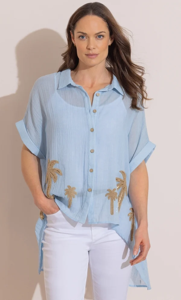 2026 Summer Wardrobe Capsule: Best Essential Pieces 17 A model wearing the Embellished Palm Relaxed Top in blue, highlighting its short sleeves, classic collar, and sequined palm hem, styled for a modern Spring capsule wardrobe women's outfit. Spring capsule wardrobe women's