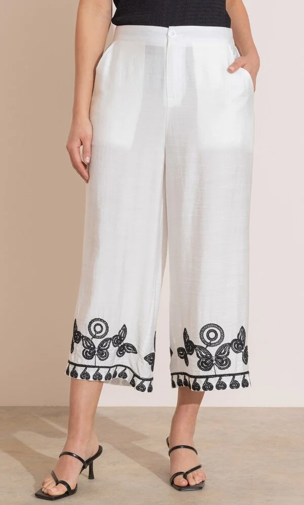 2026 Summer Wardrobe Capsule: Best Essential Pieces 20 A model wearing the Embroidered Wide Leg Cropped Trousers in white featuring a high waist, side pockets, and contrast butterfly embroidery along the cropped hem, styled for a modern 2026 summer wardrobe capsule outfit.