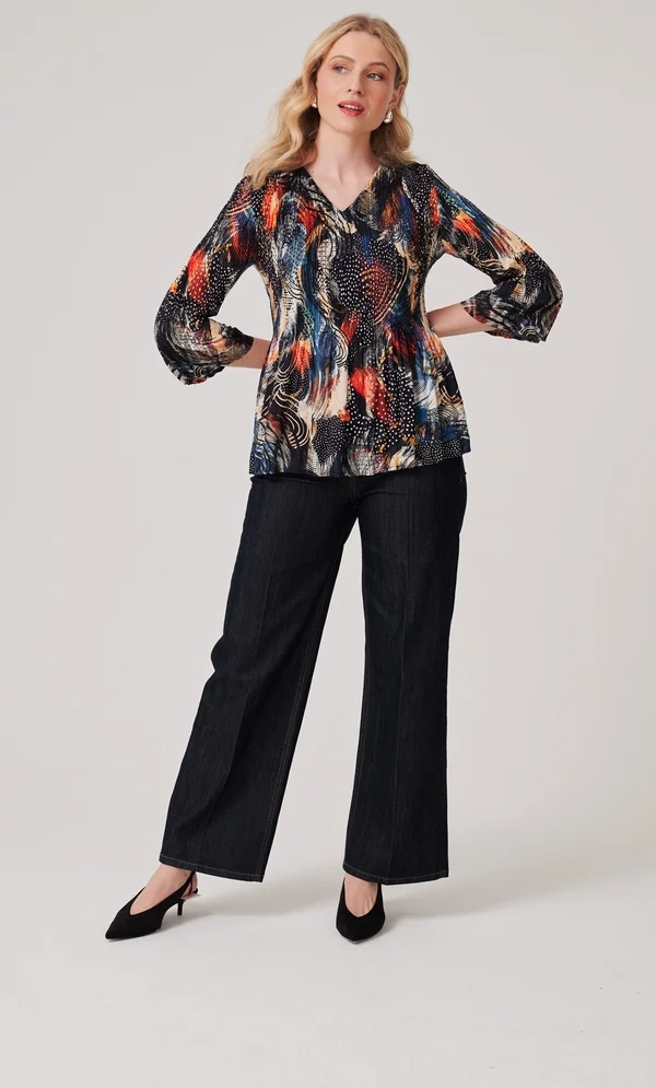 The Perfect Office Capsule Wardrobe: 2026 Work Essentials Guide 14 Studio portrait of a model wearing the Klass pleated abstract print top in black, orange, and teal with three-quarter sleeves and a V-neckline, styled for an office capsule collection.