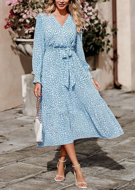 Full-length lifestyle photography of a smiling model wearing the PRETTYGARDEN Women's Floral Boho Long Sleeve Maxi Dress in dark blue floral print, highlighting the crossover V-neckline, belted waist, and tiered ruffle hem designed for wedding guests and autumn vacations. Dresses nder $50