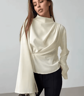 25 Minimalist Capsule Wardrobe Essentials 2026 | Timeless Pieces Every Woman Needs 7 A model wearing an elegant beige long-sleeve blouse with stylish flare cuffs and a front knot detail, styled in a modern, professional look perfect for a 2026 minimalist capsule wardrobe.