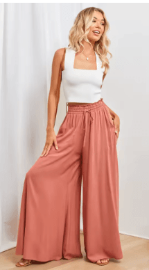 25 Minimalist Capsule Wardrobe Essentials 2026 | Timeless Pieces Every Woman Needs 17 A model wearing high-waisted, flowy wide-leg pants in a vibrant orange-red tone, styled as a highlight piece for summer capsule wardrobe essentials in a 2026 minimalist look.