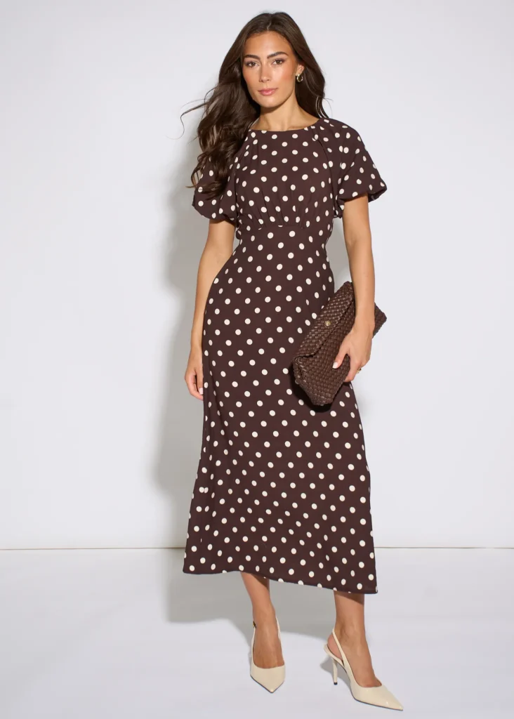 Trendy & Affordable Outfits for Women You'll Actually Love (2026) 10 A stylish woman wearing an affordable brown polka dot midi dress with puff sleeves and a fitted waist, styled for an everyday chic look featuring Trendy Outfits for Women.